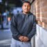Strong man leaning on brick wall. Sporty male is in sportswear. He is in city during summer.